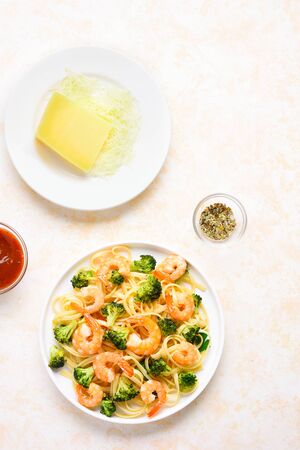 Tasty pasta with shrimp and broccoli on plate over light stone background with free text space. Tasty dish for dinner. Top view, flat layの写真素材
