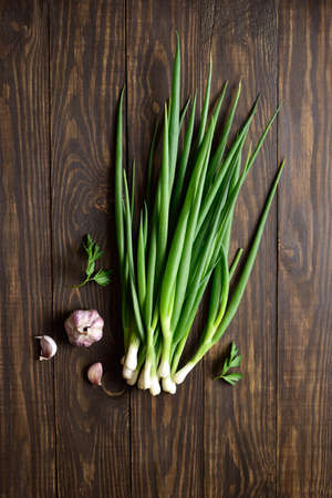 Fresh green onion and garlic on wooden background with free text space. Top view, flat layの写真素材