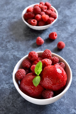 Raspberry sorbet, ice cream scoop with fresh berries in bowl over blue stone background. Tasty...