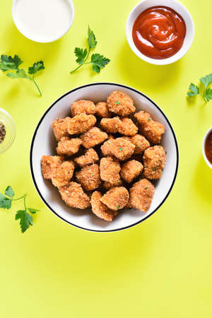 Crispy fried breaded chicken bites in bowl over yellow background with free text space. Tasty chicken nuggets. Top view, flat layの素材 [FY310158930277]