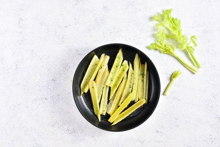 Braised celery in frying pan over light stone background with free text space. Top view, flat layの写真素材