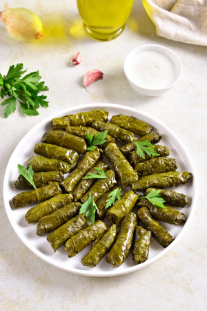 Dolma, stuffed grape leaves with rice and meat on light stone table. Close up view