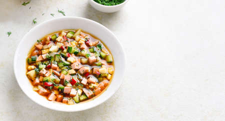 Traditional cold Russian soup Okroshka with sausage, vegetables and kvass over light stone background with free text space.の写真素材