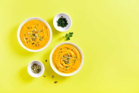 Pumpkin puree with seeds in bowl over yellow background with free text space. Healthy diet food concept. Top view, flat layの写真素材