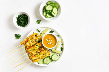 Chicken satay with peanut sauce. Grilled chicken skewers served with peanut dipping sauce. Tasty meal for dinner or party appetizers. Light background with free text space. Top view, flat layの写真素材