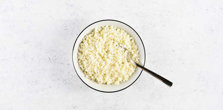 Cauliflower rice in a bowl on light stone background with free text space. Top view, flat layの写真素材