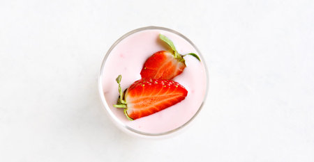 Strawberry yogurt with fresh berries in glass on light stone background with free text space....