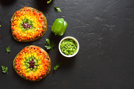 Rainbow veggie bell peppers pizza on black stone background with free text space. Vegetarian vegan...