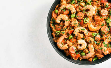 Close up view of creole jambalaya with chicken, smoked sausages and vegetables in frying pan on white stone background with copy space. Top view, flat lay, close upの写真素材