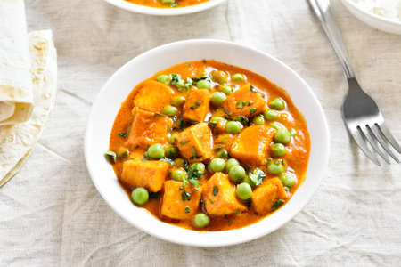 Paneer butter masala. Indian style cottage cheese curry in bowl over light background. Close up view