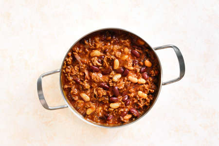 Close up view of cowboy beans with ground beef, jalapeno pepper and bacon in cooking pan over light stone background. Top view, flat layの写真素材