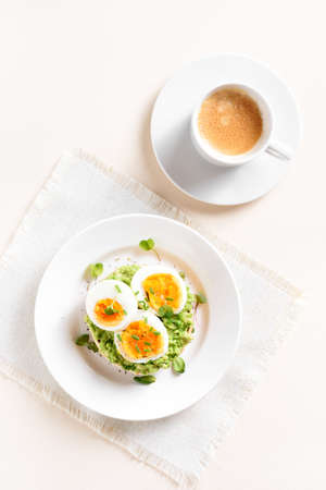 Avocado egg sandwich and cup of coffee over light stone background. Top view, flat layの写真素材
