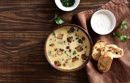 Creamy mushroom soup in bowl over wooden background with free text space. Top view, flat lay