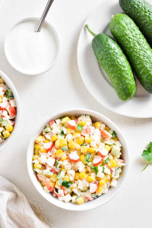 Russian style imitation crab salad with crab sticks, corn, eggs, cucumber and rice. White background, top view, flat lay, close upの写真素材