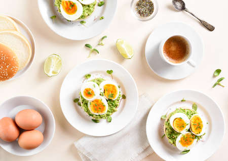 Avocado egg sandwiches over light stone background. Tasty healthy dish for breakfast or lunch. Top view, flat layの写真素材