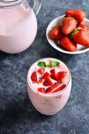 Strawberry yogurt with fresh berries in glass on blue stone background. Healthy food and drink concept.の写真素材