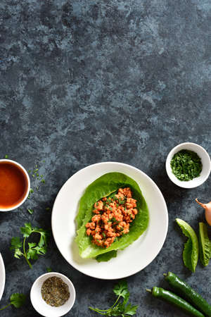 Asian minced meat lettuce wraps on blue stone background with free text space. Top view, flat layの写真素材