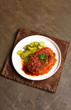 Homemade nashville style hot chicken with pickle on plate over brown background with free text space.の写真素材