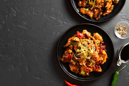 Asian chicken in sweet and sour sauce on plate over black stone background with free text space. Top view, flat layの写真素材