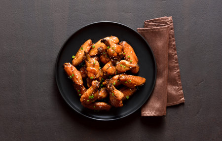 Sticky honey-soy chicken wings on plate over dark stone background. Top view, flat lay, close upの写真素材