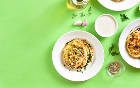 Roasted cabbage steaks on plate over green background with free text space. Top view, flat lay