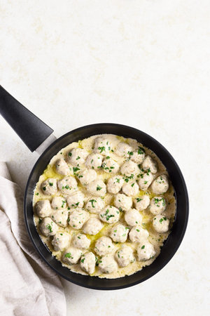 Delicious homemade swedish meatballs with creamy white sauce in frying pan over light stone background with copy space. Top view, flat lay, close upの写真素材