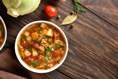 Vegetable cabbage soup in bowl over wooden background with free text space. Top view, flat layの写真素材