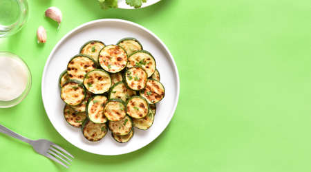 Fried zucchini on plate over green background. Top view, flat layの写真素材