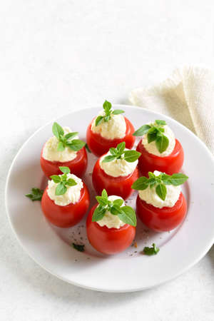 Tomatoes with cream cheese on plate over white stone background. Tasty healthy appetizer. close up viewの写真素材