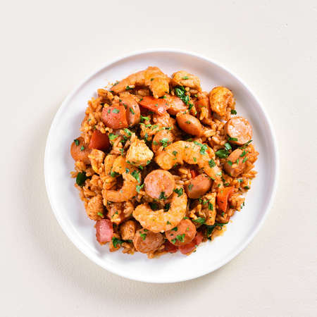 Creole jambalaya with chicken, smoked sausages and vegetables on plate over light background. Top view, flat lay, close upの写真素材