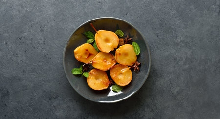 Poached pears on plate over dark stone background with copy space. top view, flat layの写真素材