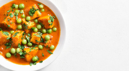 Close up view of paneer butter masala. Indian style cottage cheese curry in bowl over white stone background with copy space. top view, flat layの写真素材