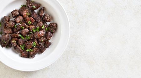 Garlic butter steak bites on plate over light stone background with copy space. Top view, flat layの写真素材