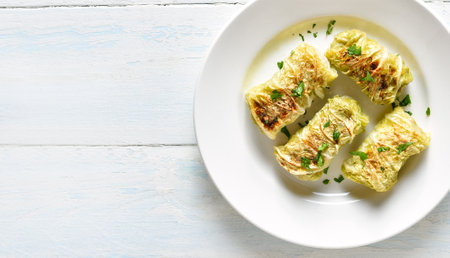 Close up view of cabbage rolls stuffed with meat on plate over light wooden background with free space. Top view, flat layの写真素材