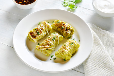 Close up view of cabbage rolls stuffed with meat on plate over light wooden background.の写真素材