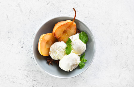 Poached pears with ice cream in bowl over light stone background with copy space. Top view, flat layの写真素材