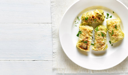 Close up view of cabbage rolls stuffed with meat on plate over light wooden background with copy space. Top view, flat layの写真素材