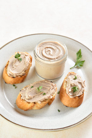 Chicken liver pate on toasted bread on plate over light background. close up view