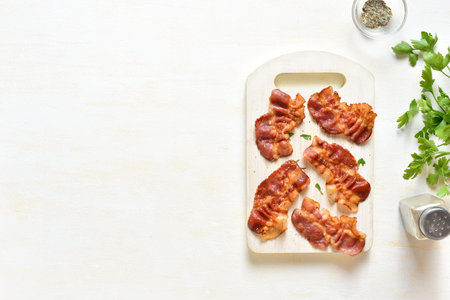 Crispy bacon on wooden cutting board over light background with copy space. Top view, flat layの写真素材