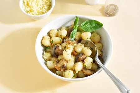 Potato gnocchi with mushroom, parmesan cheese and greens in bowl over light background. Close up viewの写真素材