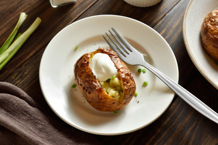 Oven baked potato on white plate on wooden table. Close up viewの写真素材