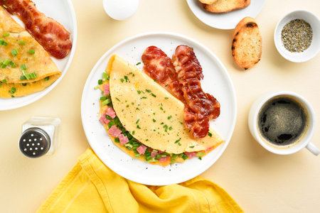 Stuffed omelet with ham and green onion and bacon over light background. Top view, flat lay.