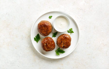 Minced pork and beef cutlets with sauce on plate over light background. Top view, flat lay