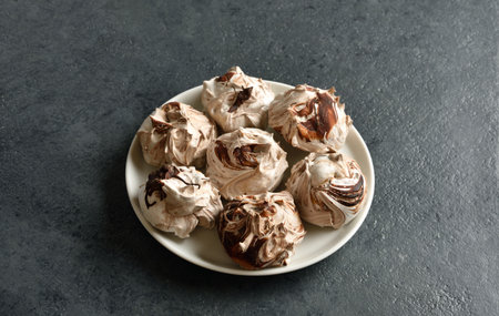 Chocolate meringue cookies on plate over dark stone background. Close up viewの写真素材