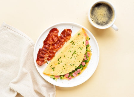 Stuffed omelette with ham and green onion and cup of coffee over light background. Tasty healthy meal for breakfast. Top view, flat lay.の写真素材