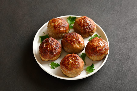 Homemade cutlets from minced meat on white plate over dark background. Tasty comfort food for...