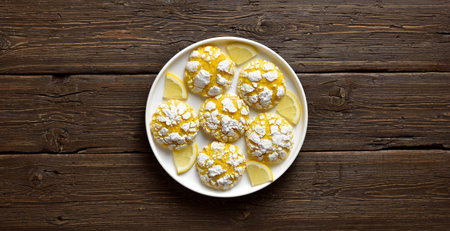 Homemade citrus cookies with lemon on white plate over rustic wooden background with free space. Top...