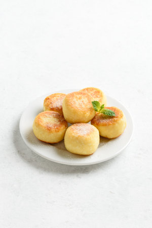 Cottage cheese pancakes (syrniki or curd fritters) on white background with free space. Healthy diet food conceptの写真素材