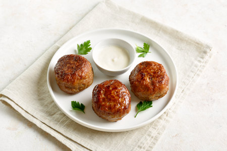 Minced pork and beef cutlets served with sauce on plate on white background. Close up viewの写真素材