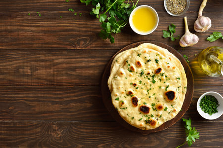 Homemade Indian naan bread with garlic butter on wooden background with free space. Top view, flat layの写真素材